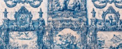 A man walking in front of a a beautiful blue tile wall in Porto, Portugal.